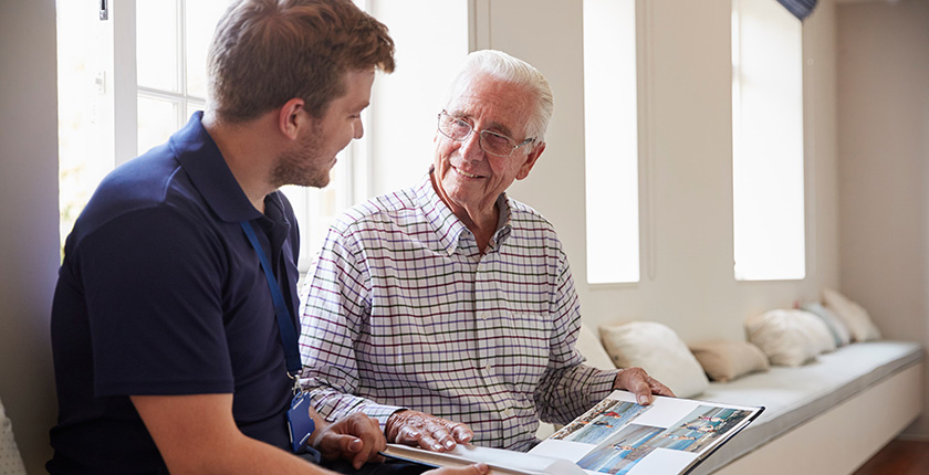 Caregiver sharing a photo album with a resident in a bright, comfortable common area.