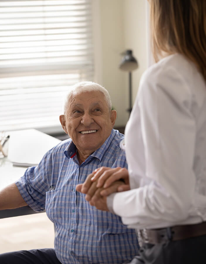 Elderly man holding hands of a caregiver smiling